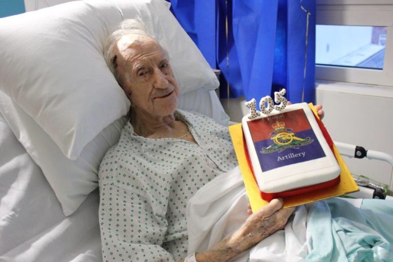 George on a hospital bed holding his cake