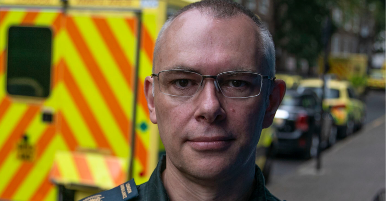 Close up of Darren Farmer with ambulances in background