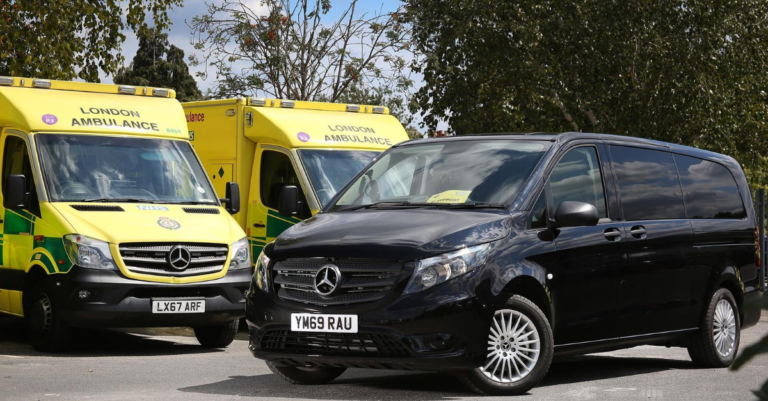 Black Mercendes van next to two ambulances