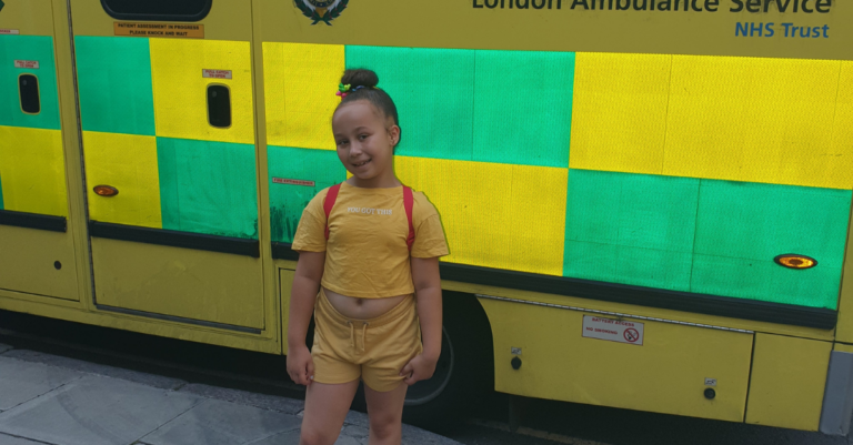 Ariana smiling photographed stood in front of an ambulance