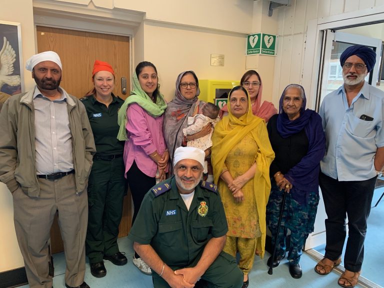A picture of Ron Dhesi, LAS colleague Lucinda, his family and community leaders, standing by the Woolwich Gurdwara defibrillator.