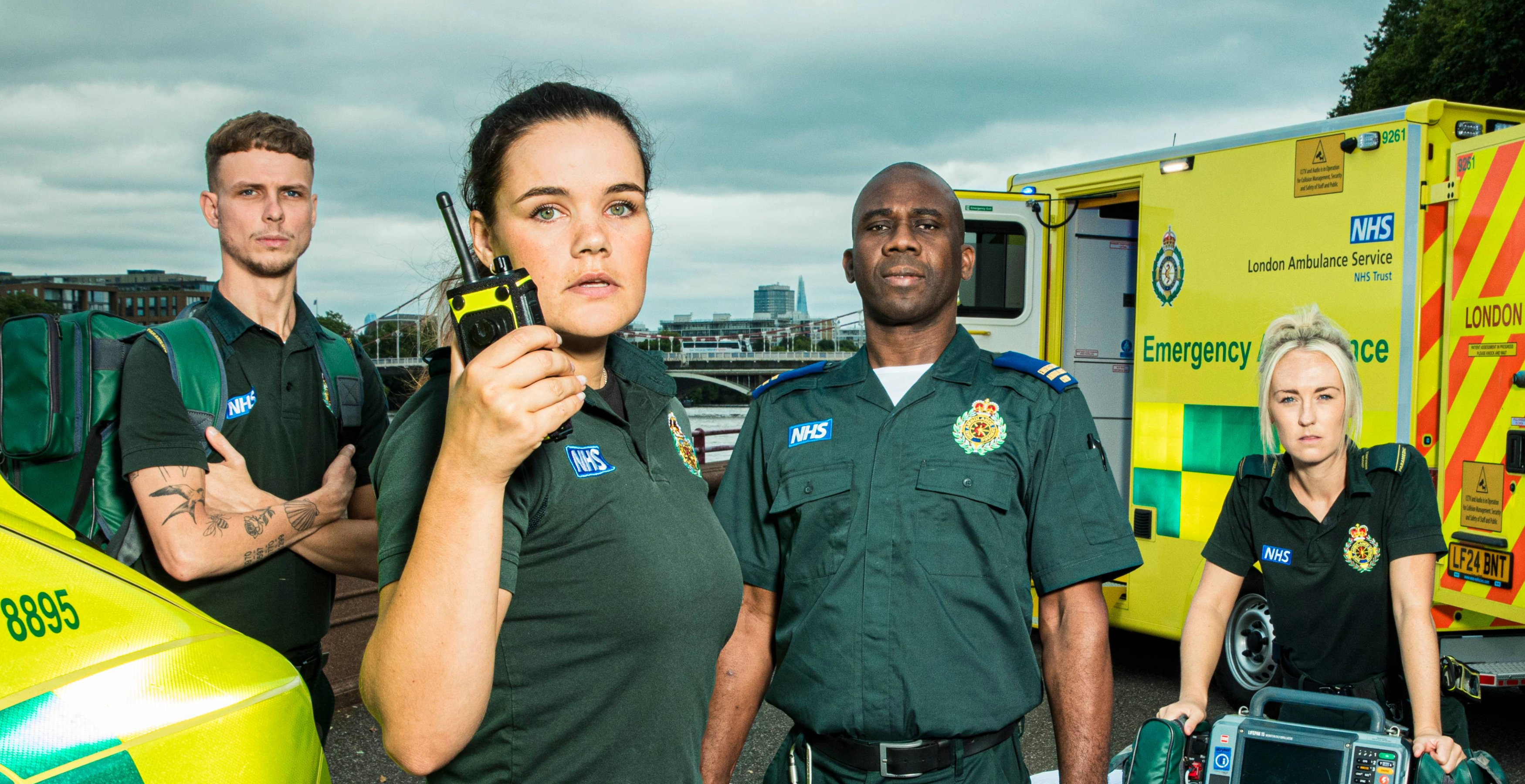 BBC Ambulance stars standing in front of an ambulance setting with one person using a crew radio.