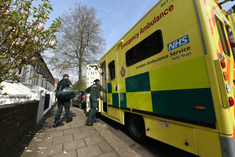 Two clinicians leaving a patient's home and stepping back in to the ambulance.