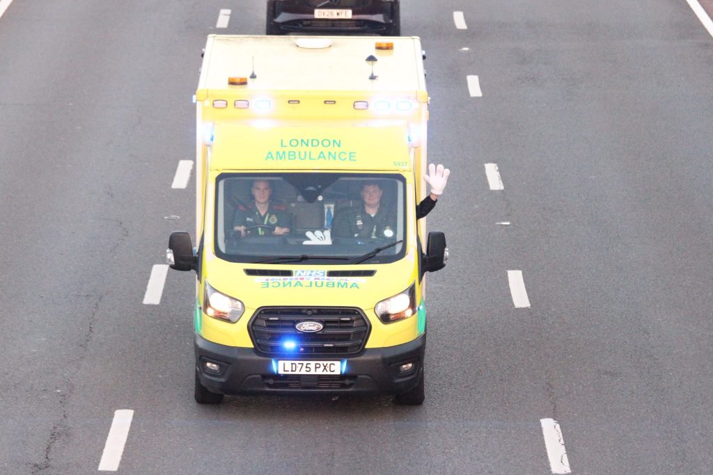 Paramedics driving ambulance, waving out the window with Mickey hand