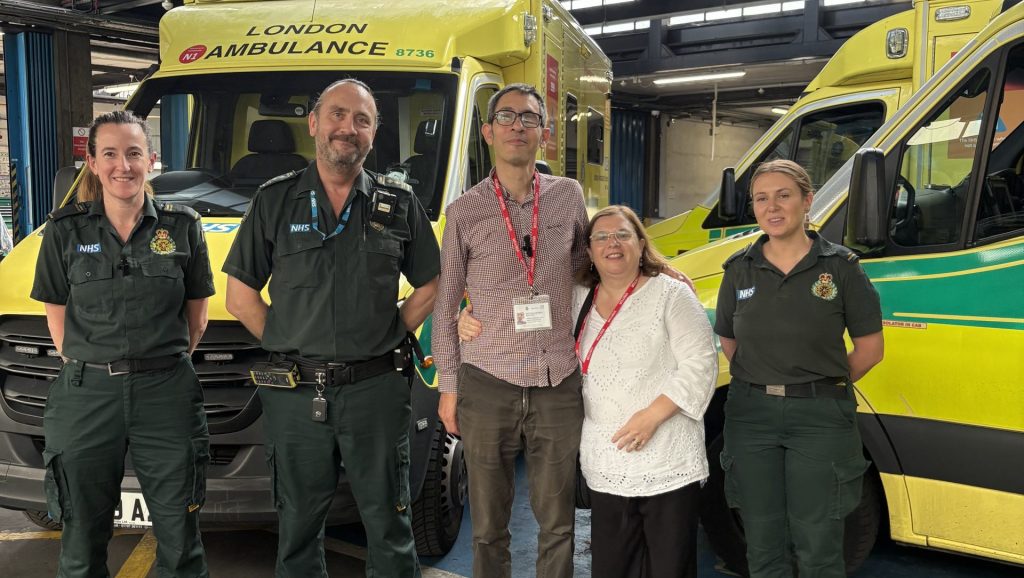 Patient Victor with his wife and paramedic crews that rescued him standing in front of an ambulance