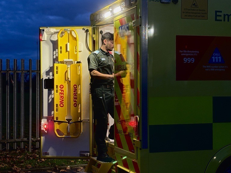 A clinician in the back of an ambulance on a dark autumn evening.