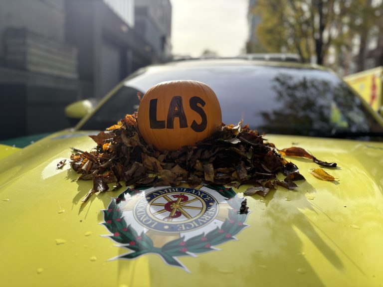 A pumpkin sitting in a pile of leaves on a London Ambulance Service fast response car, with ‘LAS’ written on it in black marker.